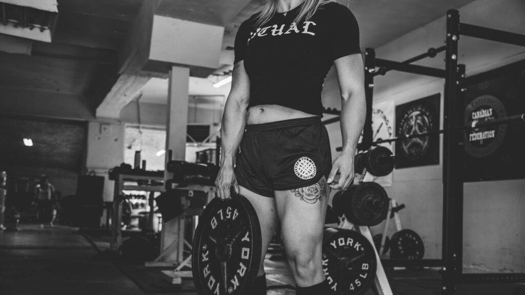 Vrouw met halterschijf in sportschool tijdens krachttraining voor spieropbouw