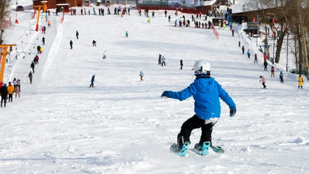 Snowboarder op drukke piste tijdens wintersport vakantie met andere wintersporters