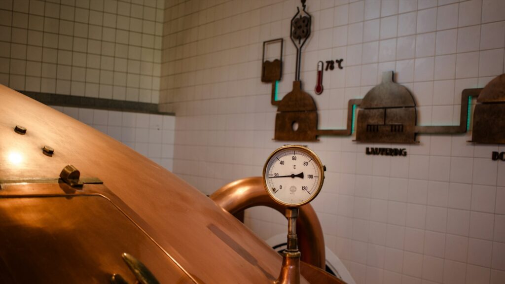 Koperen brouwketel met thermometer tijdens productie van gefermenteerde dranken in een brouwerij